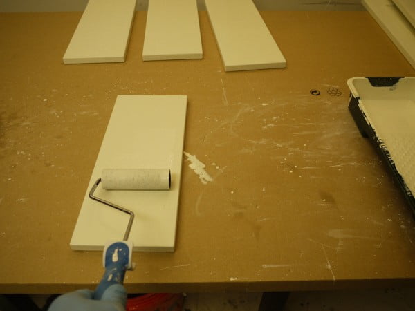 Finish coating the cabinet drawers by first rolling on a uniform coat of paint using the 3 inch roller.