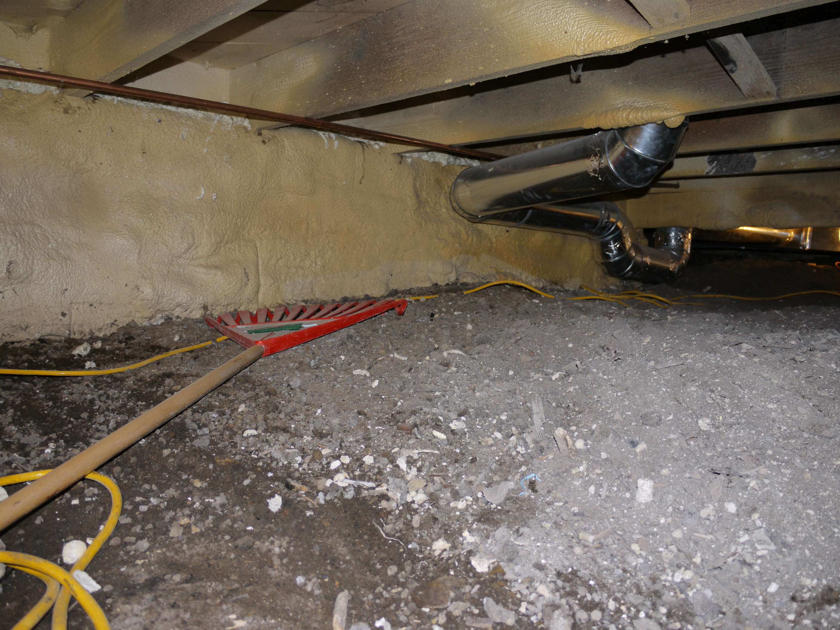 Crawl space cleaning and leveling with garden rake.