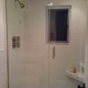 Completed walk in tile shower with heavy glass partial wall and heavy glass door installed.