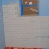 Continue to tile up shower wall maintaining plumb and level. Cut shorter pieces to fill in gaps at the corners.
