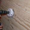 Use drill with hole saw attachment to cut hole in plywood at the center of the screw marks.