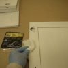 Removing sanding dust from primed kitchen cabinet door with tack cloth.