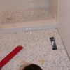 Use a covered piece of 2 x 4 to help level and embed shower pan and floor tiles.