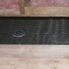 Shower pan construction - view of framing, tar paper, wire mesh and drain base.