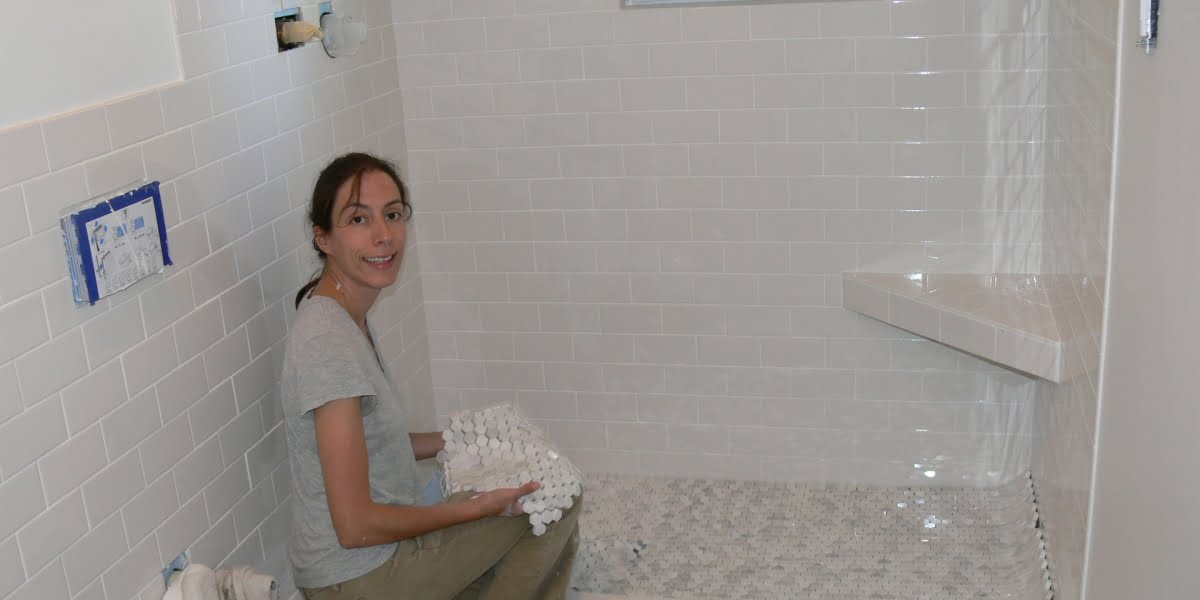 Elena shows off the freshly tiled shower walls and prepares to tile the shower pan.