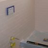 Wall finished over concealed toilet unit with white subway tile mounted on cement board tile backer.