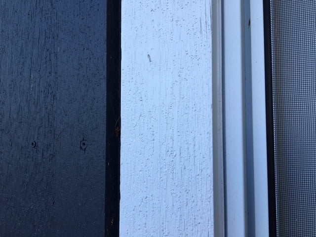 Close up of window caulking detail for board and batten siding. Caulk the gap between the window frame and the widow trim board. No caulk is applied to the outside (siding) edge of the window trim.