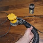 Orbital sander attached to vacuum to limit dust while sanding.