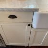 Finished results of painting our Ikea kitchen cabinets shown with white Carrara marble counters and white farm sink.