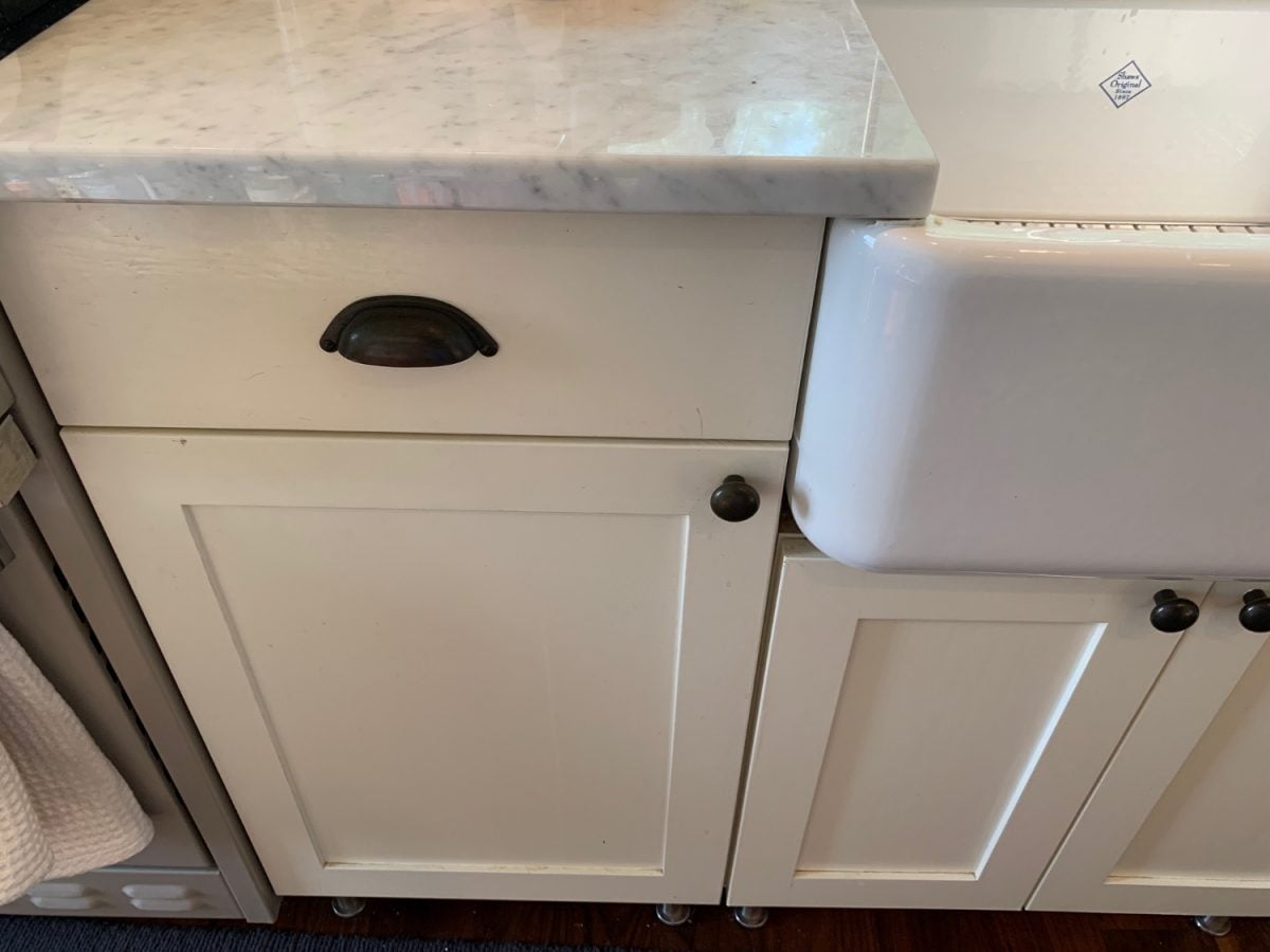 Finished results of painting our Ikea kitchen cabinets shown with white Carrara marble counters and white farm sink.