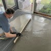 Self-leveling mortar leveled with a screed board over radiant heat.